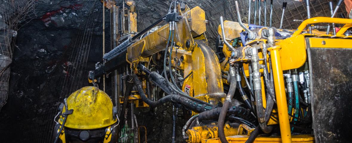workers wearing safety clothing and helmets working with machiney in a mine