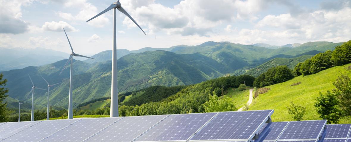 Mountains with solar panels and wind turbines in foreground