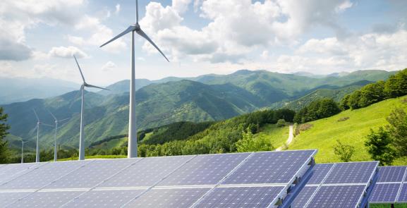 Mountains with solar panels and wind turbines in foreground